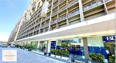 a large building on a street with benches in front of it at Hawaii Suite by Guest Reservations Manila in Manila