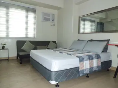a bedroom with a bed and a mirror and a chair at SonSon at Manhattan Plaza Tower 1, Araneta, Cubao, Quezon City in Manila