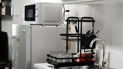a kitchen sink with a rack of utensils next to a refrigerator at Smart Cozy Home Air Residences Makati in Manila