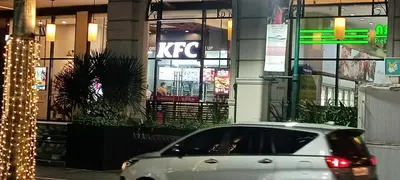 a silver car parked in front of a kfc building at Hilander's Condotel near Terminal 3 Airport in Manila
