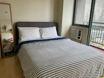 a bedroom with a bed with a striped comforter and a window at SHAW BLVD 69 sqm 2 bdrm w/ WiFi, parking, across Shangrila Mall in Manila