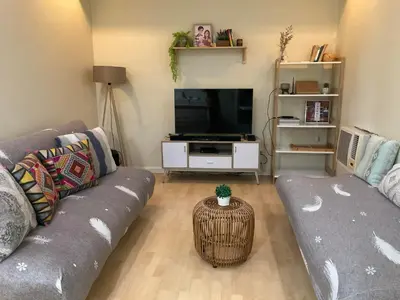 a living room with a gray couch and a tv at SHAW BLVD 69 sqm 2 bdrm w/ WiFi, parking, across Shangrila Mall in Manila