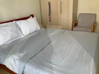 a white bed with a chair in a room at SHAW BLVD 69 sqm 2 bdrm w/ WiFi, parking, across Shangrila Mall in Manila