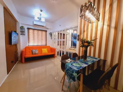 a living room with an orange couch and a table at Modern Minimalist Condo near Airport in Manila