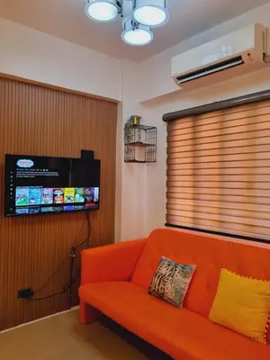 a living room with an orange couch and a flat screen tv at Modern Minimalist Condo near Airport in Manila