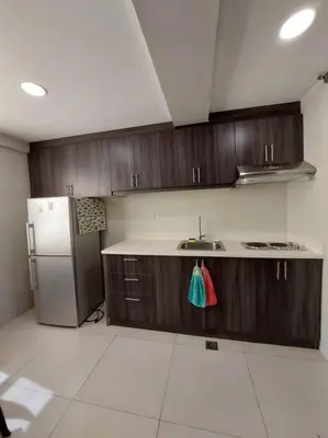 a kitchen with wooden cabinets and a stainless steel refrigerator at 2BR Loft unit in Manila