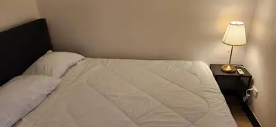 a bedroom with a white bed with a lamp and a night stand at Casa Antonio at Fairway Terraces Family Penthouse 2BR Wi-Fi Nr Golf, Airport, Fort BGC in Manila
