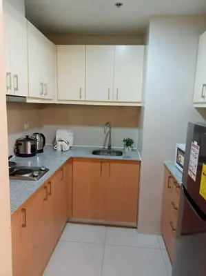 a small kitchen with white cabinets and a sink at Beautiful High End Condo in City Center, Manila in Manila
