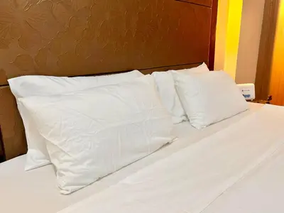 a bed with white sheets and pillows on it at Kiel 4-Star Condo Hotel Near NAIA Manila Airport Terminal in Manila