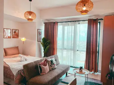 a bedroom with a bed and a couch and a window at Studio Unit Viceroy Residences McKinley Hill BGC in Manila