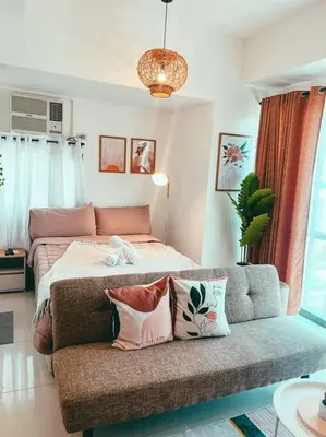 a bedroom with a bed and a couch with pillows at Studio Unit Viceroy Residences McKinley Hill BGC in Manila