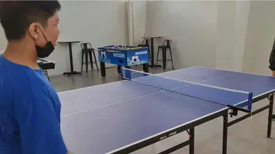 a man is looking at a ping pong table at Cozy Studio with Beautiful View & FREE Netflix Access in Manila
