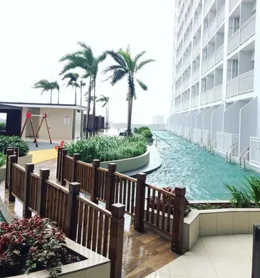 a pool in the middle of a building with palm trees at Breeze Residences with Ocean view by Bmars in Manila