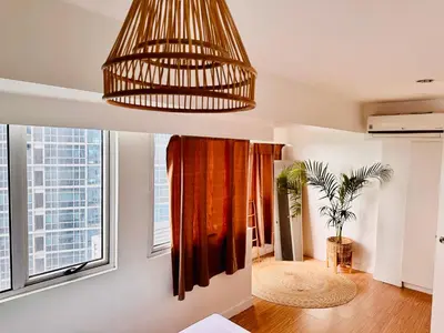 a living room with a large window and a chandelier at 2Bedroom Loft Type Unit in BGC by K Suites in Manila