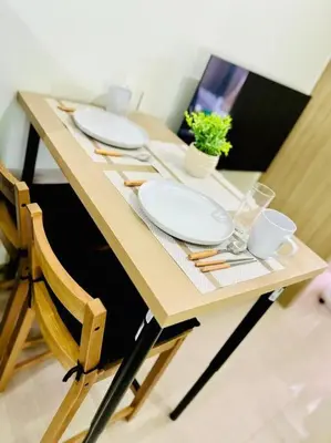 a wooden table with two plates and a plant on it at Cozy 1BR at Shore 2 with balcony in Manila