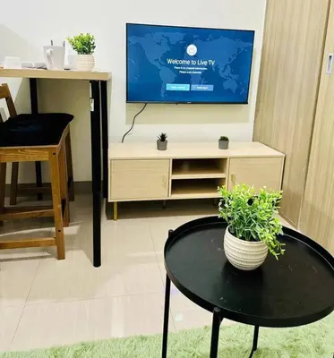 a living room with a table and a flat screen tv at Cozy 1BR at Shore 2 with balcony in Manila