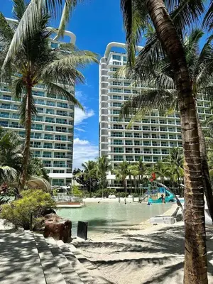 a view of a resort from the beach with palm trees at Azure resort Paranaque deluxe 8 plus 2toddler free in Manila