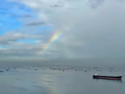 a boat in the water with a rainbow in the sky at Residential Resort Condo by the Bay in Manila