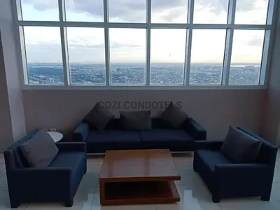 a living room with couches and a table and a large window at The Beacon Makati by Cozi Condotels in Manila