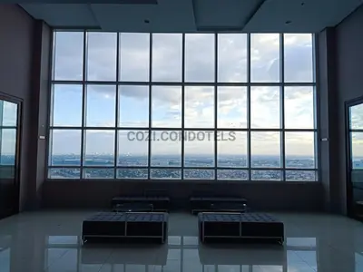 a room with three beds in front of a large window at The Beacon Makati by Cozi Condotels in Manila