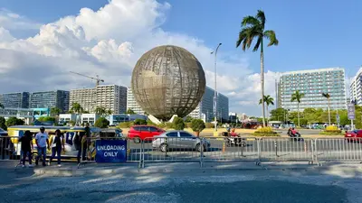 a large globe in a parking lot with cars and buildings at ART's Nest at Shore Residences in Manila