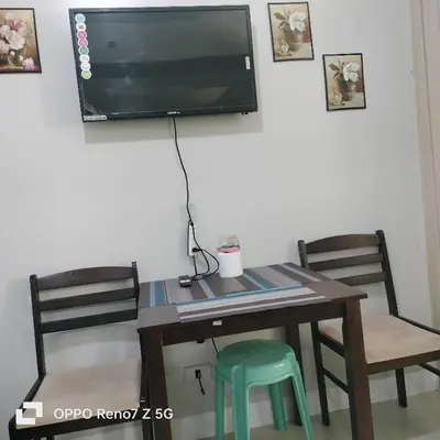 a dining room table with two chairs and a tv on the wall at Glenda Place Aurum At Sea Residences near Moa in Manila