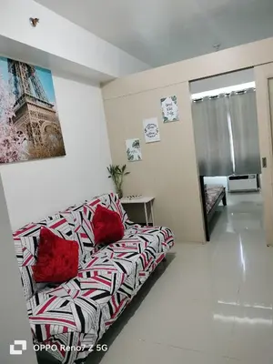a living room with a couch with red pillows at Glenda Place Aurum At Sea Residences near Moa in Manila