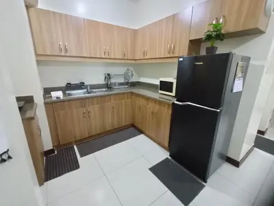 a kitchen with a black refrigerator and wooden cabinets at Acacia Estates Taguig in Manila