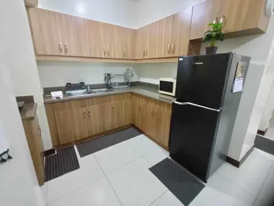 a kitchen with a black refrigerator and a sink at Acacia Estates Taguig in Manila