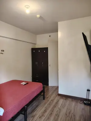 a room with a bed and a black cabinet at Acacia Estates Taguig in Manila
