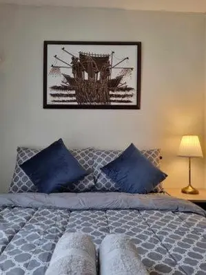 a bedroom with a bed with blue pillows and a picture on the wall at Casa REYNA at KASARA Urban Residences in Manila