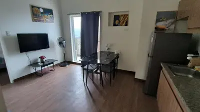 a living room with a table and a kitchen with a television at Prisma residence Celeste tower PH 16B with fully furnished and fast wifi for rent in Manila
