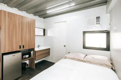 a small bedroom with a bed and a sink at District Inn in Manila