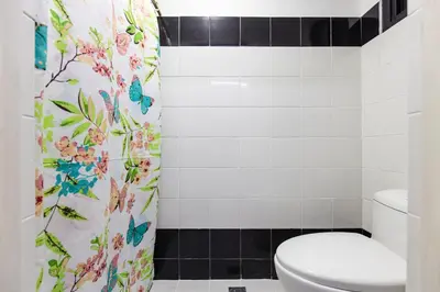 a bathroom with a toilet and a shower curtain with butterflies at District Inn in Manila