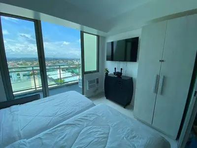 a bedroom with a white bed and a balcony at Uno Staycation in Manila
