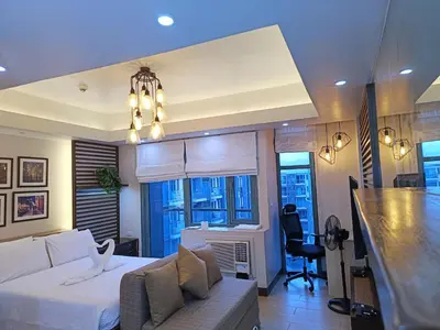 a living room with a white bed and a bar at Two Palmtree Villas Across Manila Airport Terminal 3 -JJRMK Condotel in Manila