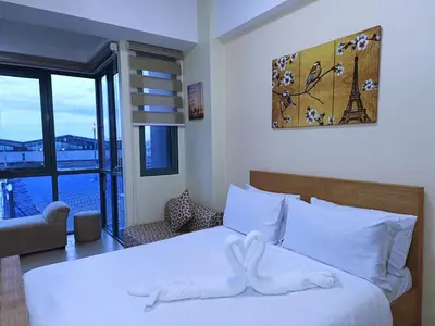 a bedroom with a large white bed with a window at Near Terminal 3 Two Palmtree Villas- Walking distance only (JJRMK) in Manila