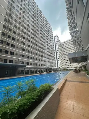 a large building with a swimming pool in front of it at Suzi's Place @ Green 2 Residences Free Wi-fi & Netflix in Dasmariñas