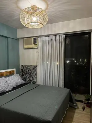 a bedroom with a bed and a window and a chandelier at Relax@Samaya Pasig in Manila