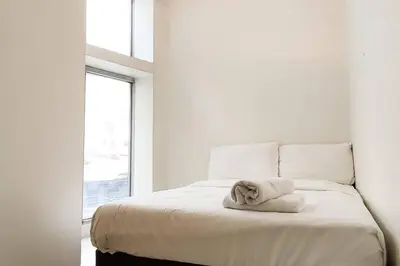 a white bedroom with a bed with a towel on it at JP Santiago Studio Makati J206 in Manila
