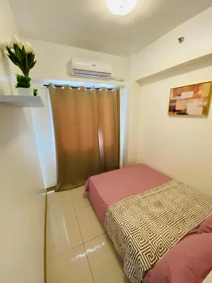 a small bedroom with a bed and a window at Luxury Two Bedroom with Balcony in SOUTH RESIDENCE of Las Pinas in Manila