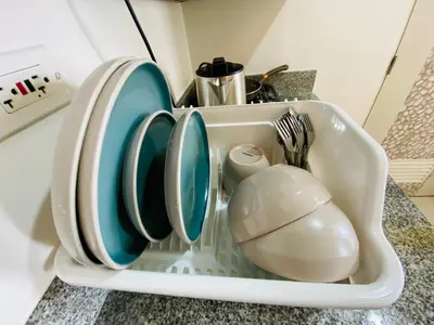 a sink with plates and utensils in it at Luxury Two Bedroom with Balcony in SOUTH RESIDENCE of Las Pinas in Manila