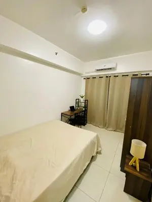 a bedroom with a bed and a table and a desk at Luxury Two Bedroom with Balcony in SOUTH RESIDENCE of Las Pinas in Manila