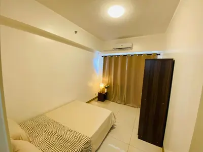 a small bedroom with a bed and a window at Luxury Two Bedroom with Balcony in SOUTH RESIDENCE of Las Pinas in Manila