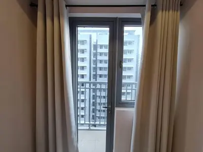 a window with curtains and a view of a building at Chic 2 Bedroom EDSA APT with Balcony in Manila