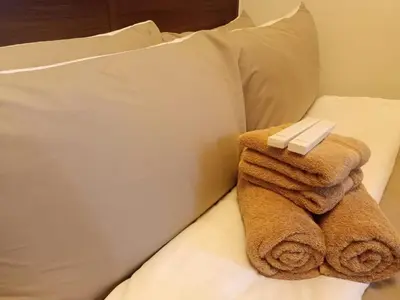 a pile of towels sitting on top of a bed at AIR Luxury Makati CBD with balcony in Manila