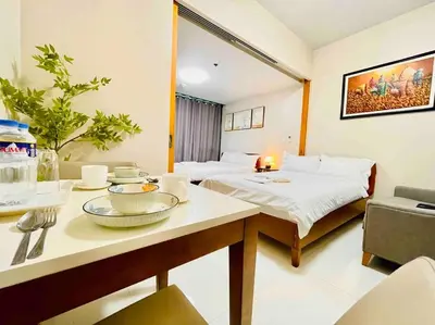a hotel room with a bed and a table with bowls and plates at One Uptown 2-bed 1BR w/XBOX, Netflix in BGC in Manila