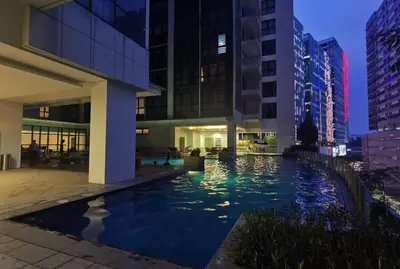 a swimming pool in the middle of a city at night at One Uptown 2-bed 1BR w/XBOX, Netflix in BGC in Manila