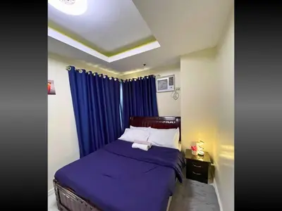 a bedroom with a purple bed with a blue curtain at 40 Percent Promo Off This Month, Balcony Ocean View Plus Free Pool & Sauna Access Exclusive 2025 Rates at Walking Distance US Embassy, Front of Robinsons Place MANILA, Bellagio and Experience Breathtaking Manila Bay Views in Manila