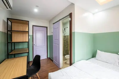 a bedroom with a bed and a desk and a bathroom at St. Marvin Studio Makati M308 in Manila